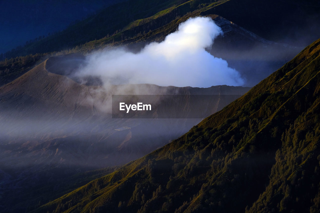 Smoke emitting from volcanic mountain against sky