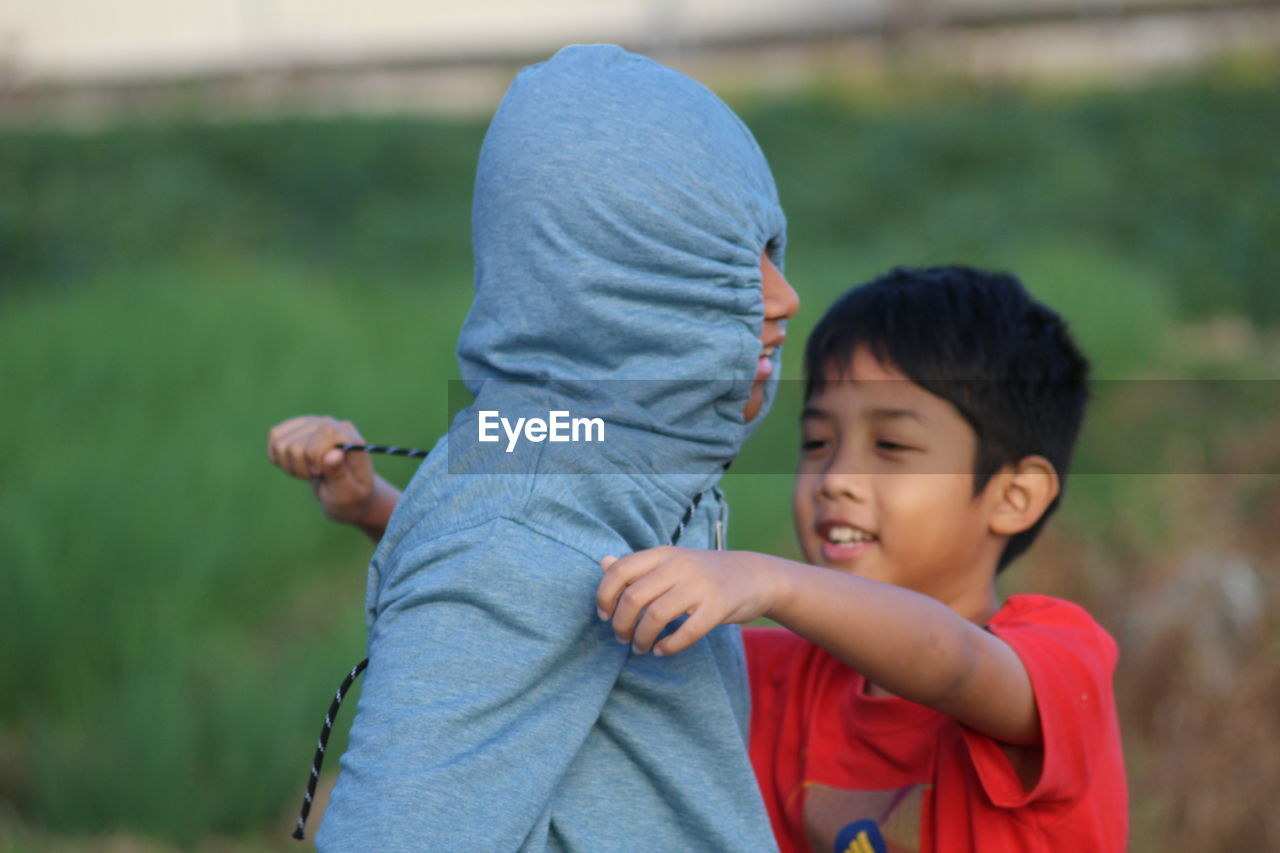 Boy tying friend with rope on field