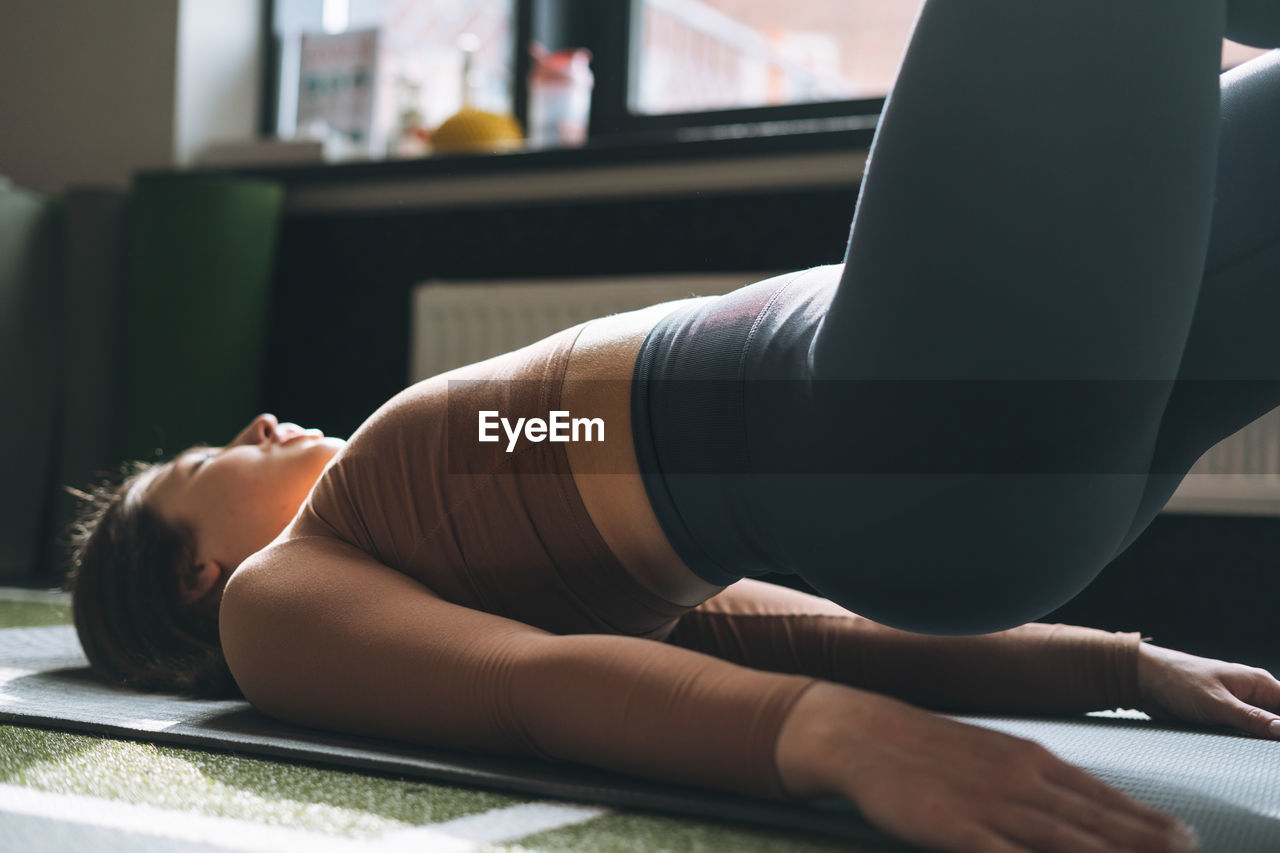 Young brunette woman doing stretching pilates, practice yoga on mat in fitness club