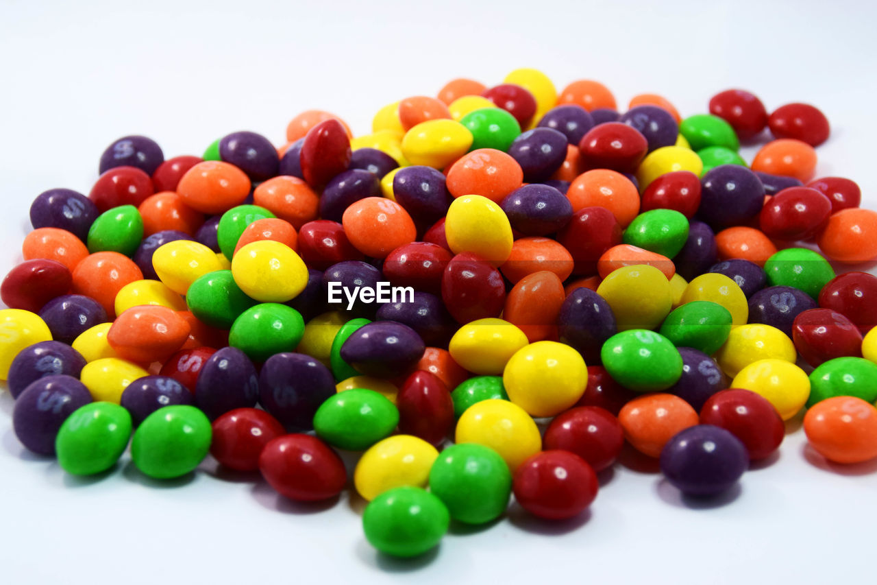 CLOSE-UP OF MULTI COLORED CANDIES IN WHITE BACKGROUND