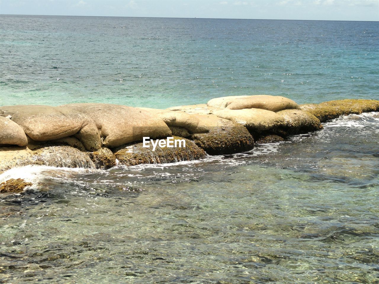 Rocks on sea shore against clear sky