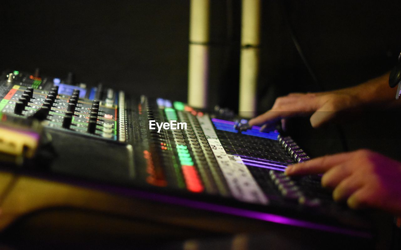 Cropped hand of man operating sound mixer at music concert