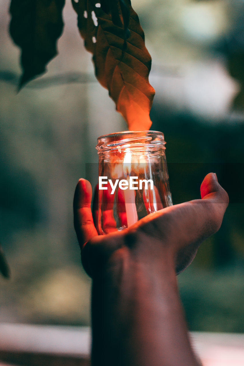 Close-up of hand holding burning candle