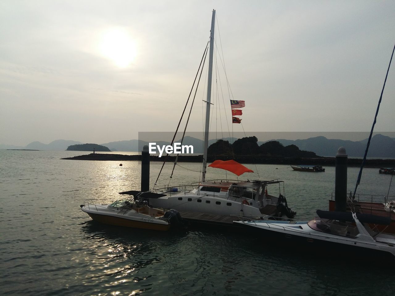 Sailboats moored in sea against sky