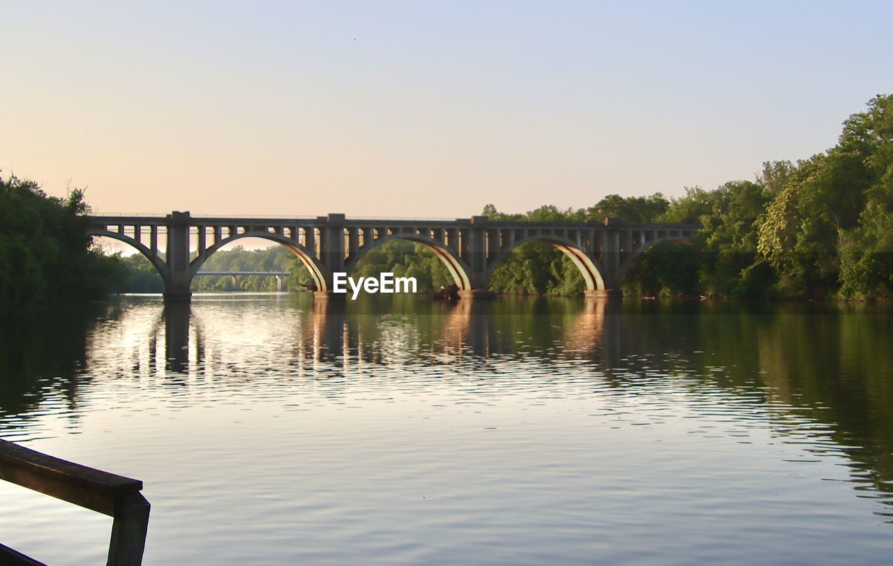 water, bridge, reflection, sky, architecture, built structure, river, nature, transportation, clear sky, morning, arch, no people, tranquility, arch bridge, travel destinations, tree, beauty in nature, outdoors, scenics - nature, plant, landscape, travel, tranquil scene, environment, sunlight, copy space, day, reservoir, body of water