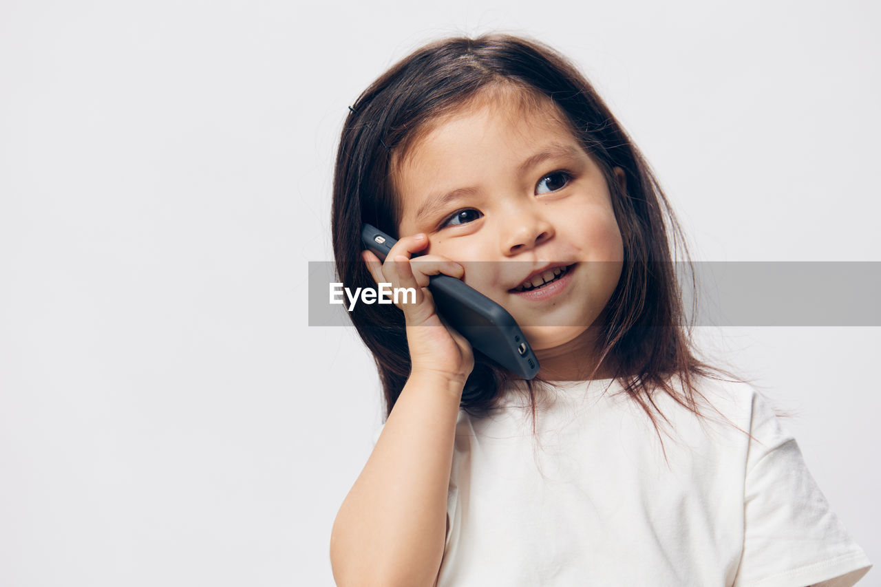 portrait of young woman talking on mobile phone against white background