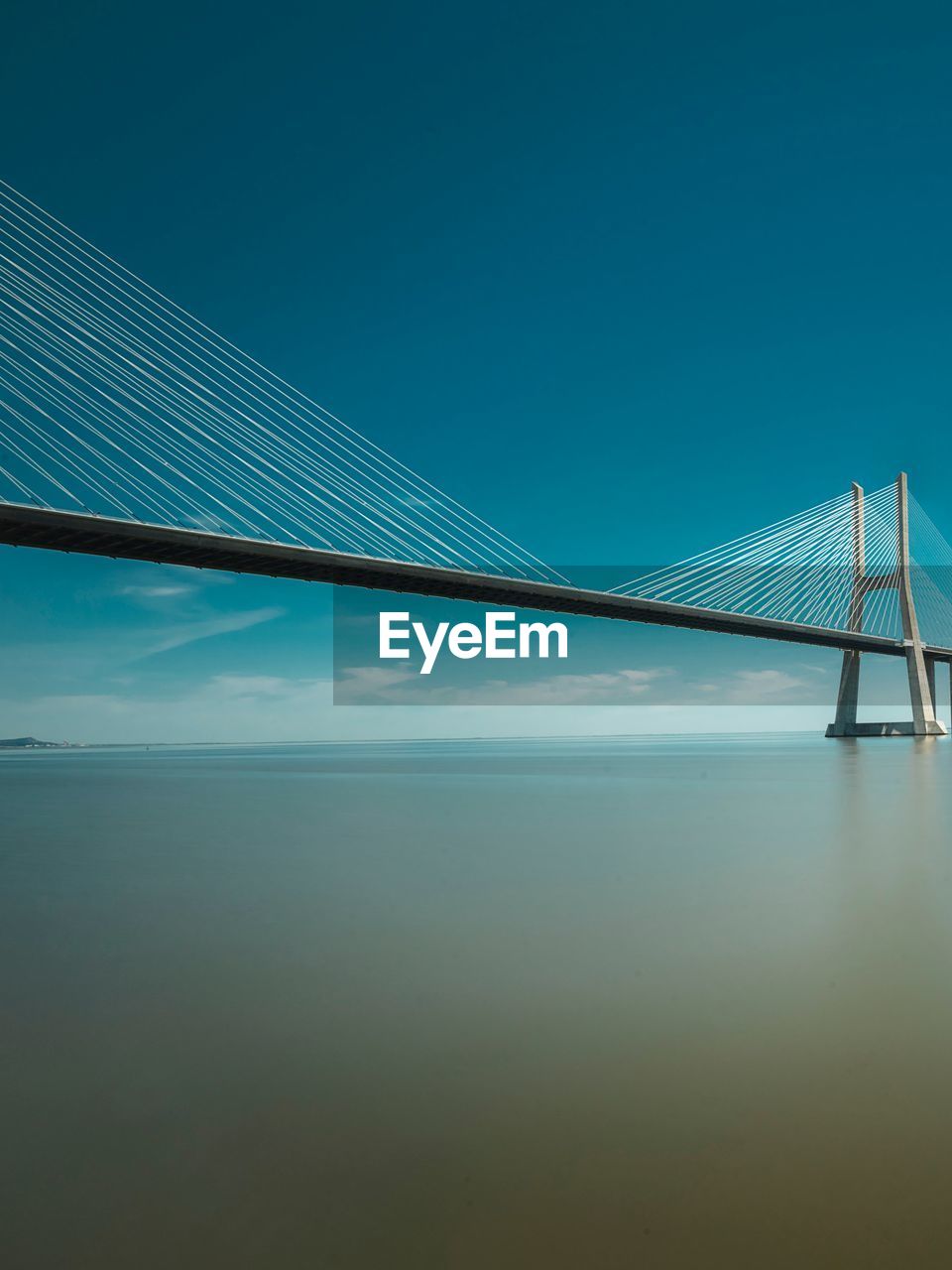 Suspension bridge over sea against blue sky