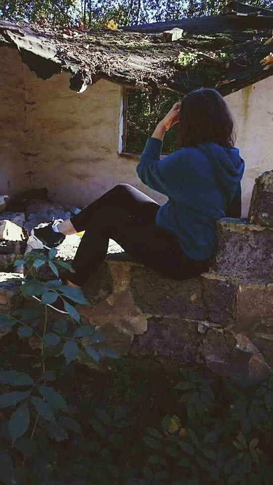 FULL LENGTH OF WOMAN SITTING ON WALL