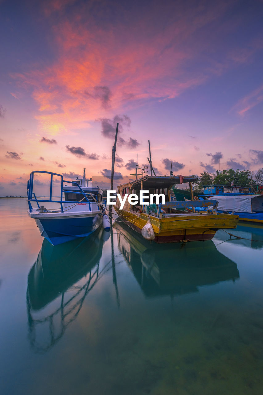 Boats moored in sea during sunset