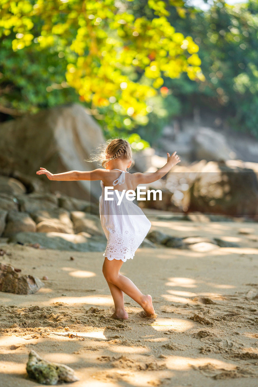 full length of young woman standing on sand at beach