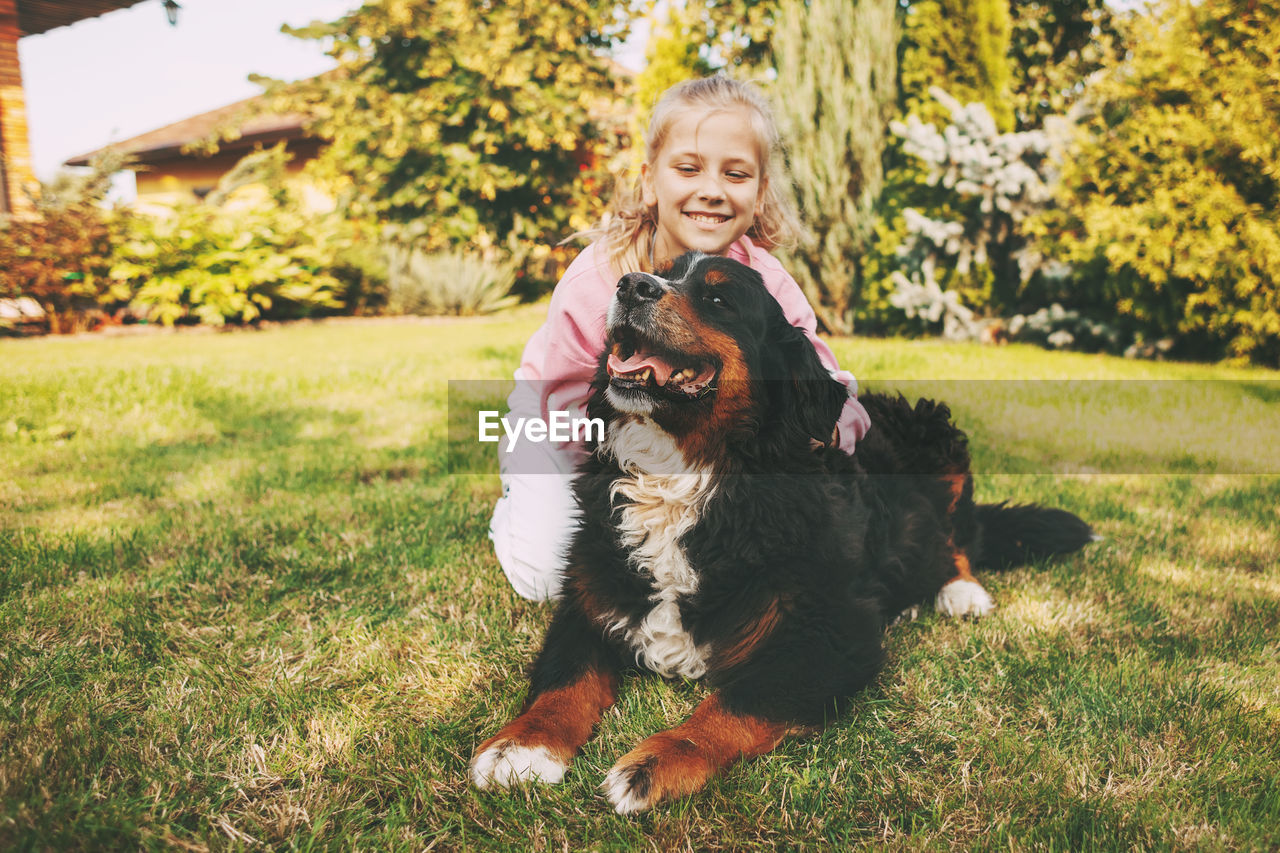 Smiling girl sitting with dog at lawn