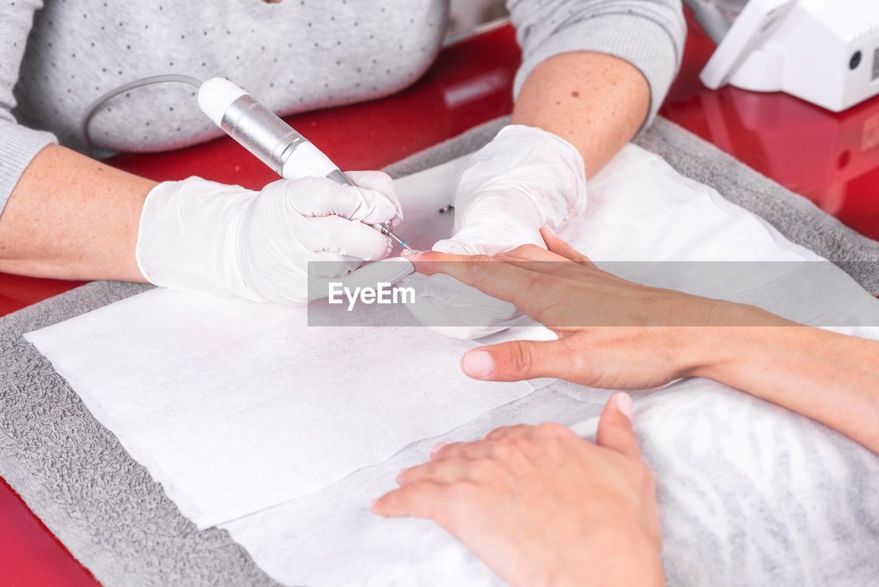 Midsection of beautician doing manicure of female customer in salon