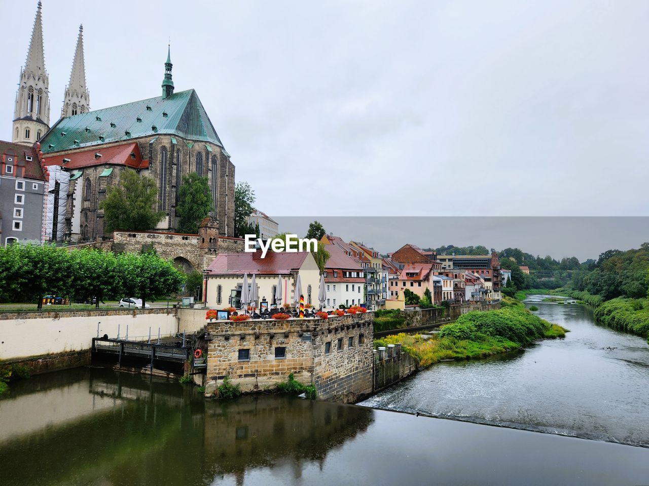 Buildings by river against sky