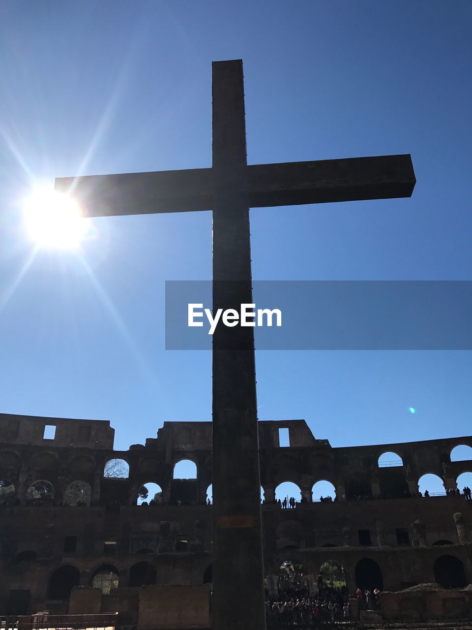 Low angle view of cross against blue sky on sunny day