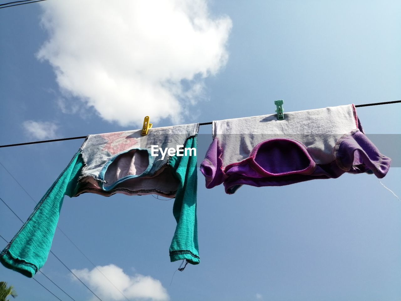 LOW ANGLE VIEW OF CLOTHES HANGING ON CLOTHESLINE AGAINST SKY
