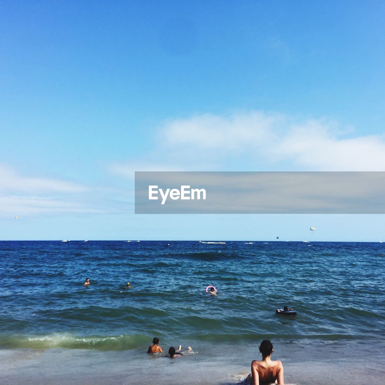 PEOPLE SWIMMING IN SEA AGAINST SKY