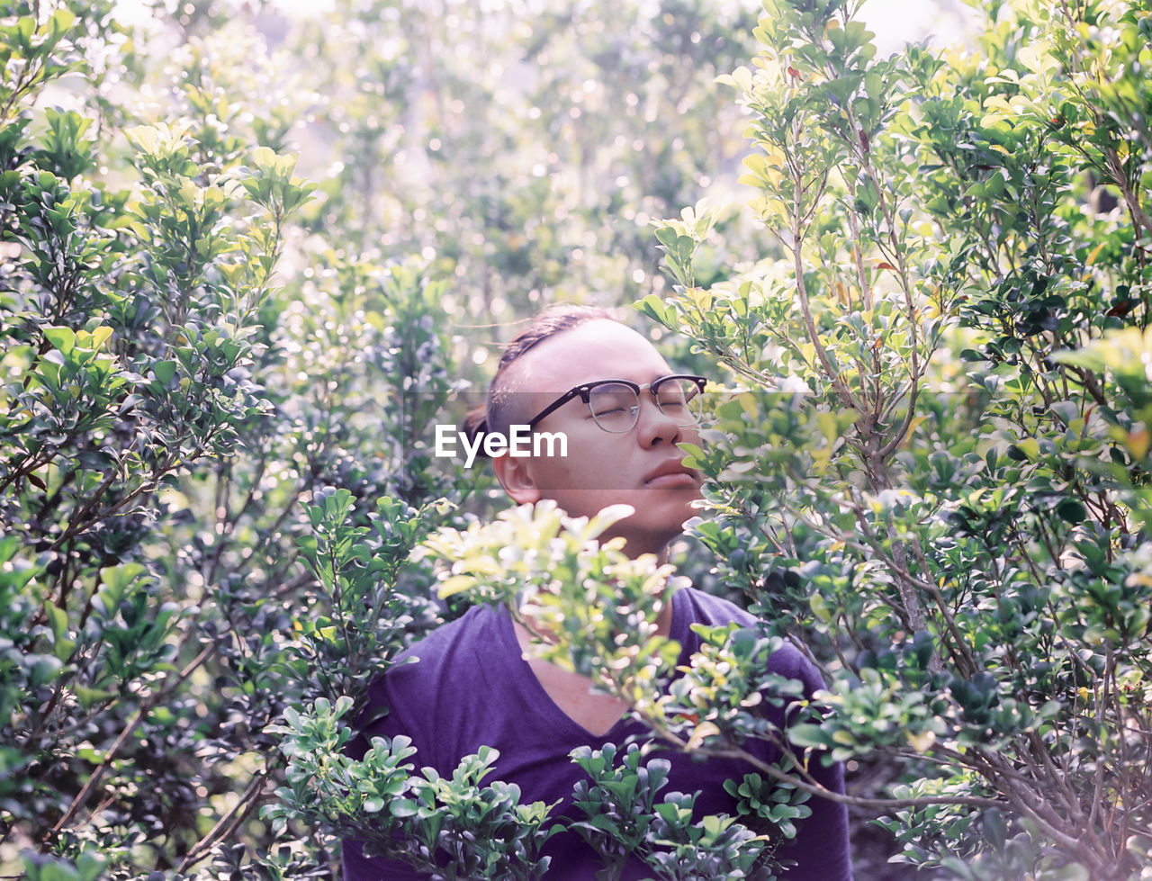 Young man standing amidst plants at park