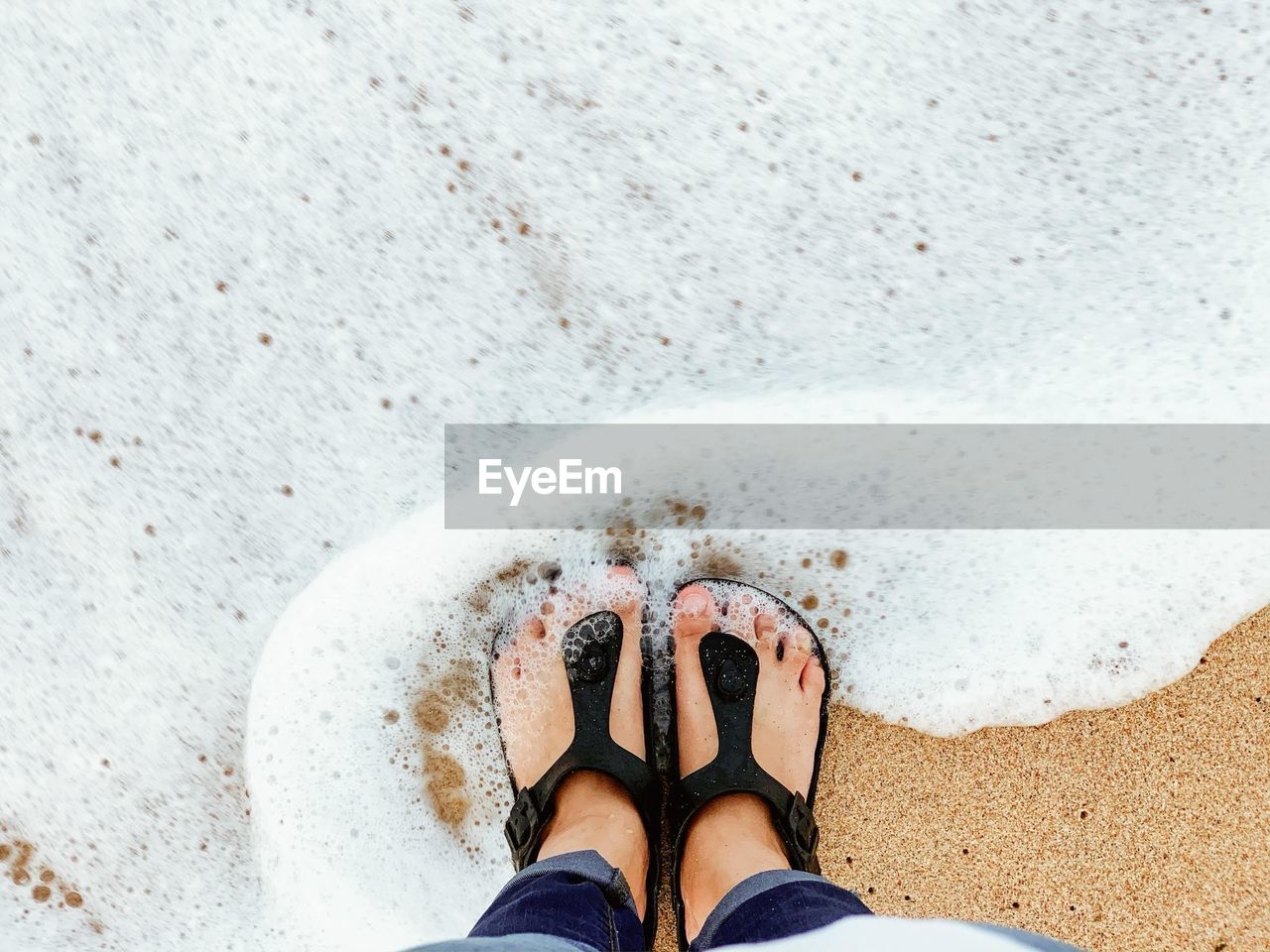 Low section of person standing on sand