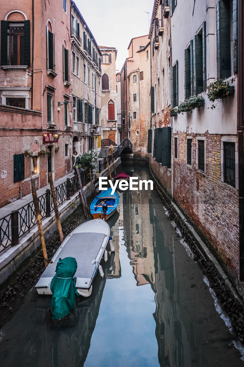 Boats moored in canal amidst buildings