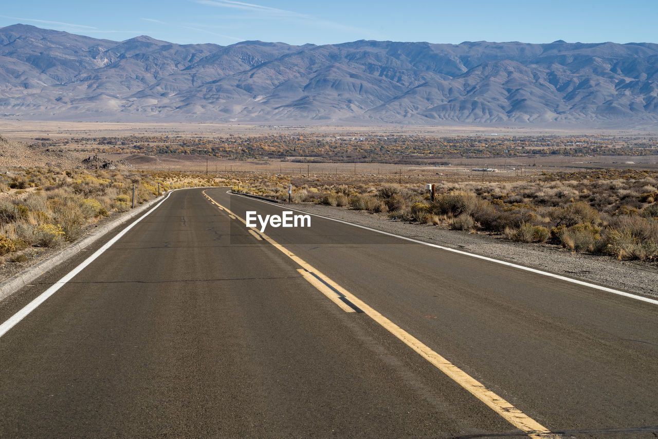 Empty road along desert landscape toward distant mountains