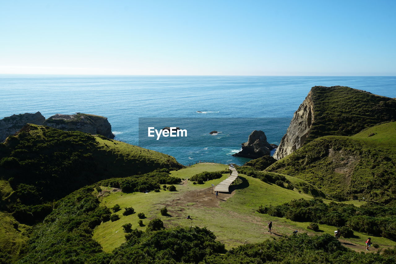 HIGH ANGLE VIEW OF ROCKS ON SEA AGAINST CLEAR SKY