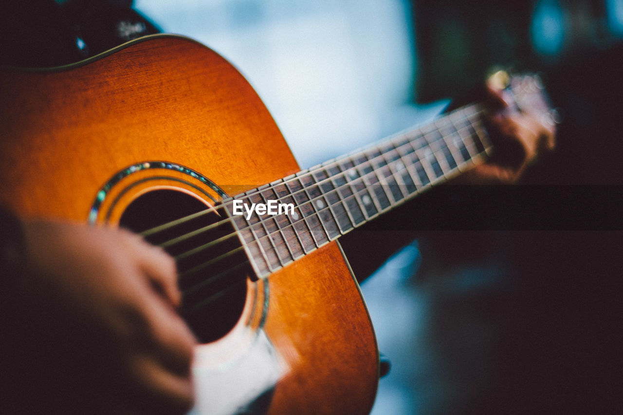 Cropped hands of man playing acoustic guitar