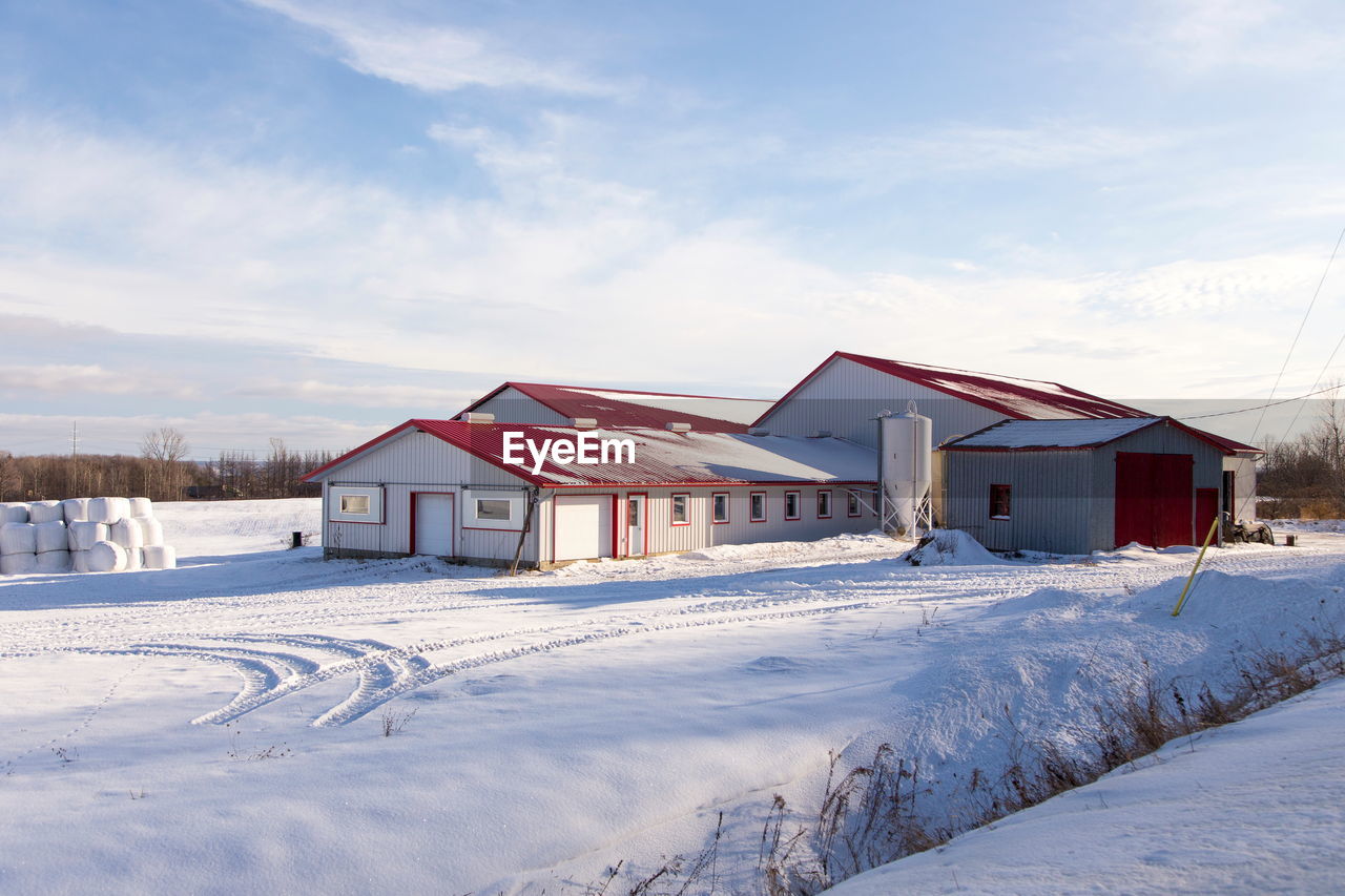 HOUSES ON SNOW COVERED FIELD BY BUILDING AGAINST SKY