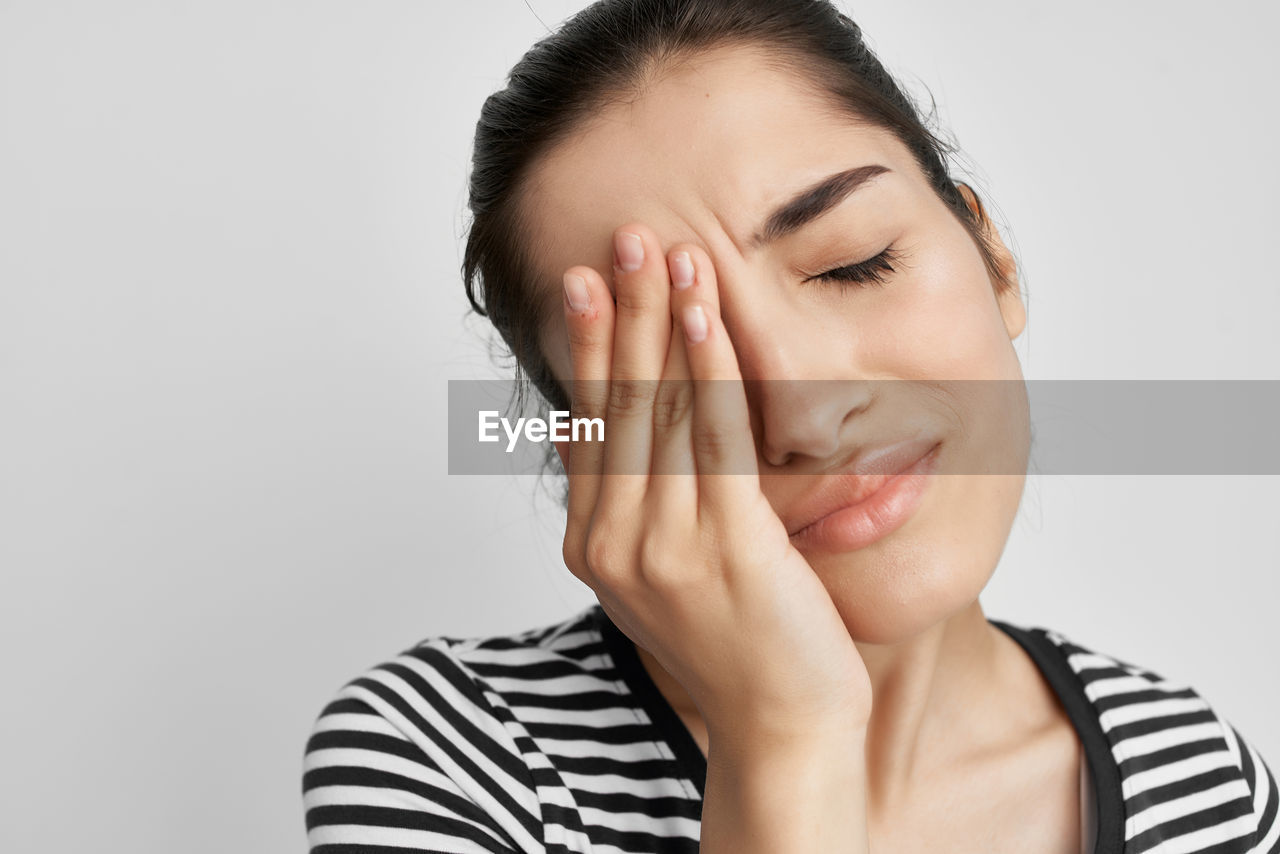 PORTRAIT OF BEAUTIFUL WOMAN AGAINST GRAY BACKGROUND