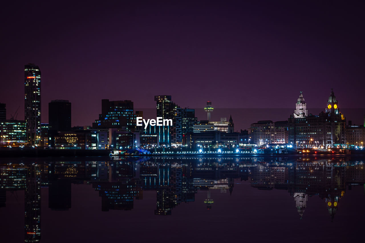 Reflection of illuminated cityscape on water at night