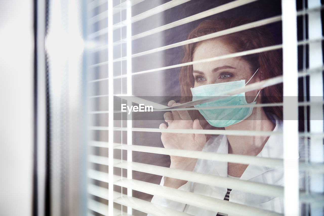 Close-up of doctor looking away through blinds