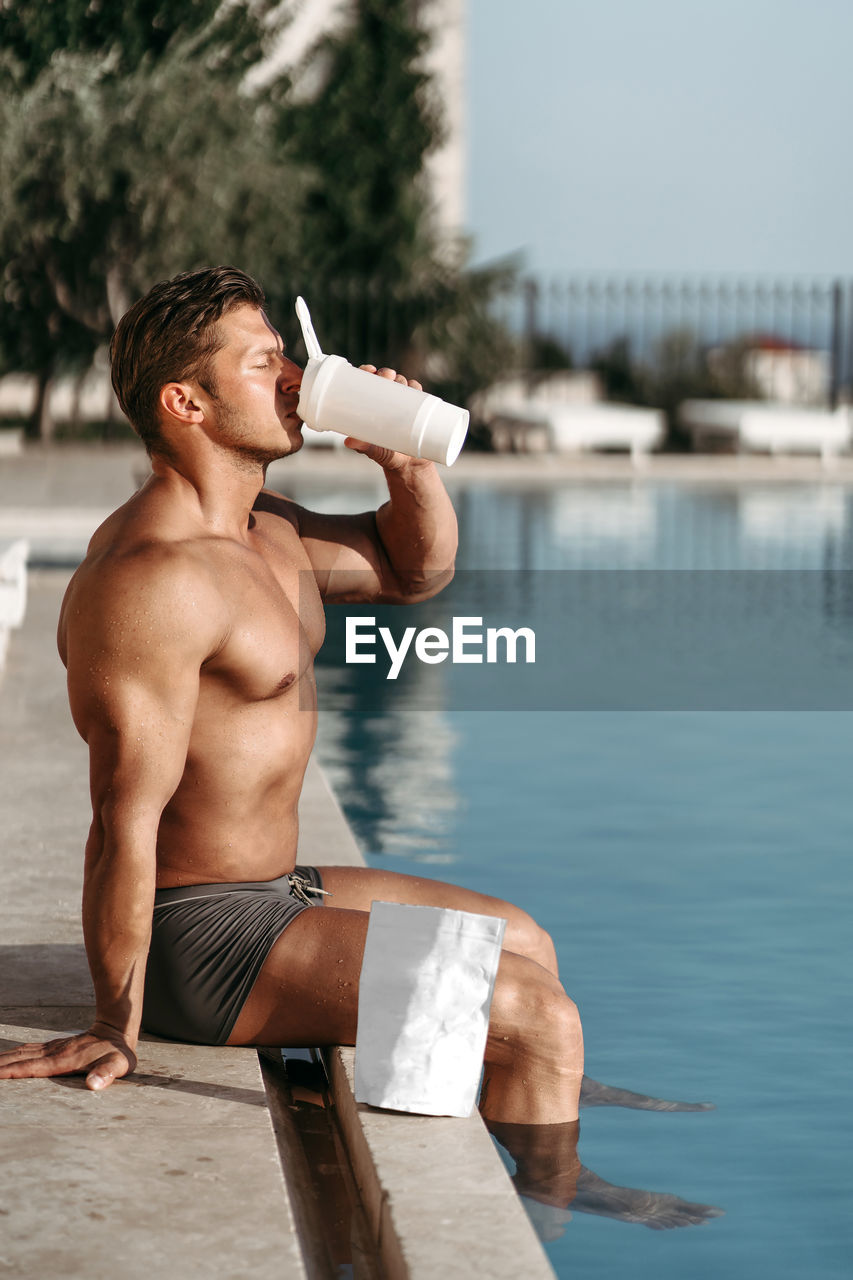 Side view of muscular man drinking protein shake