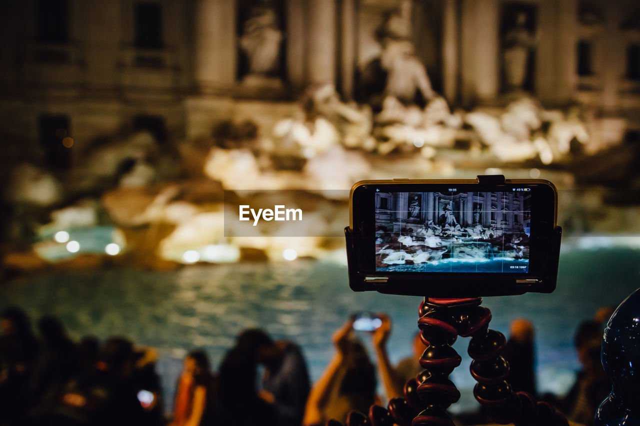 Fountain in front of historical building reflecting in mobile phone