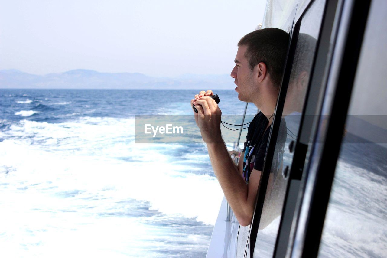 Man looking through window of van at beach