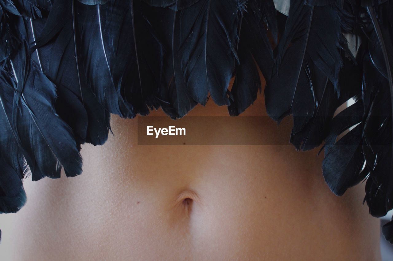 Midsection of young woman wearing black feather costume