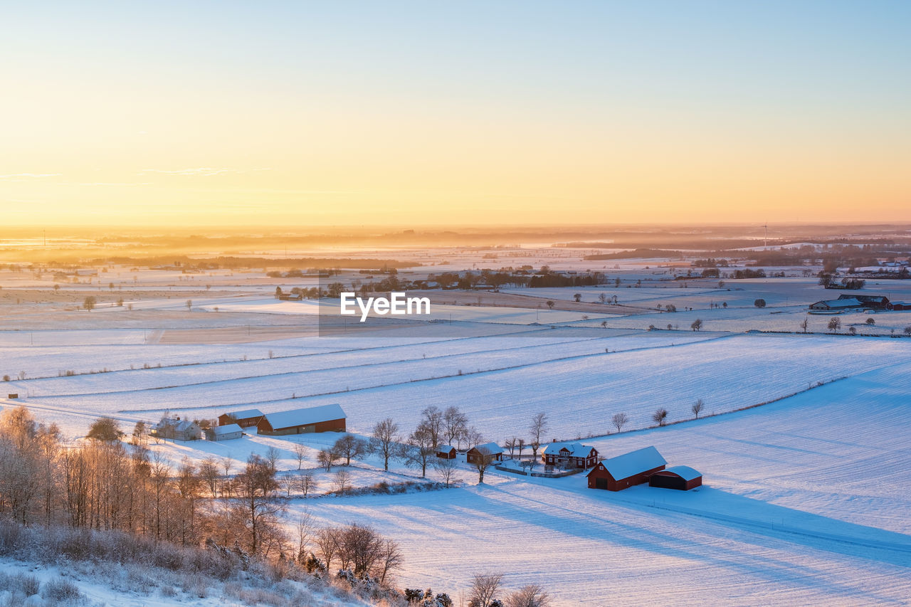 Scenic view of snow covered field against sky during sunset