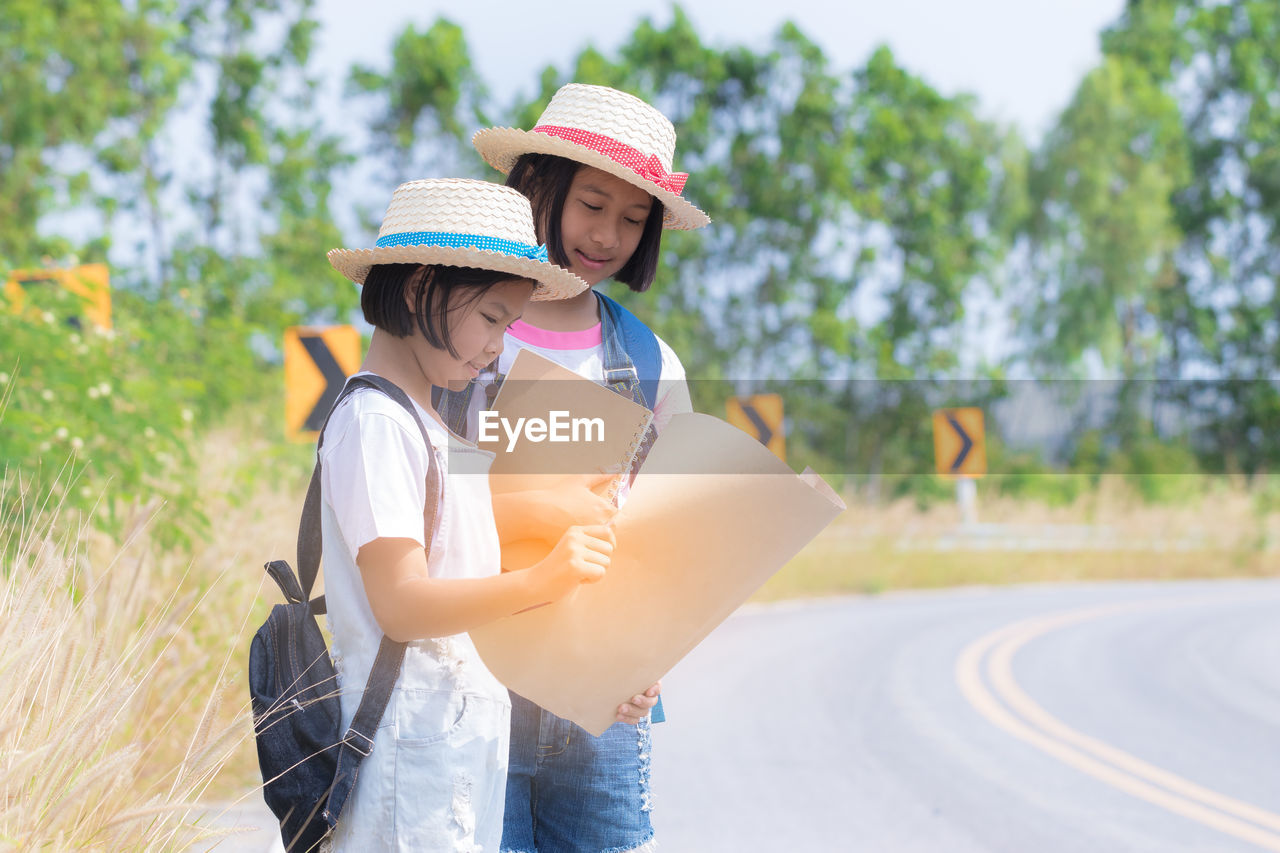 Girls looking at map while standing on road