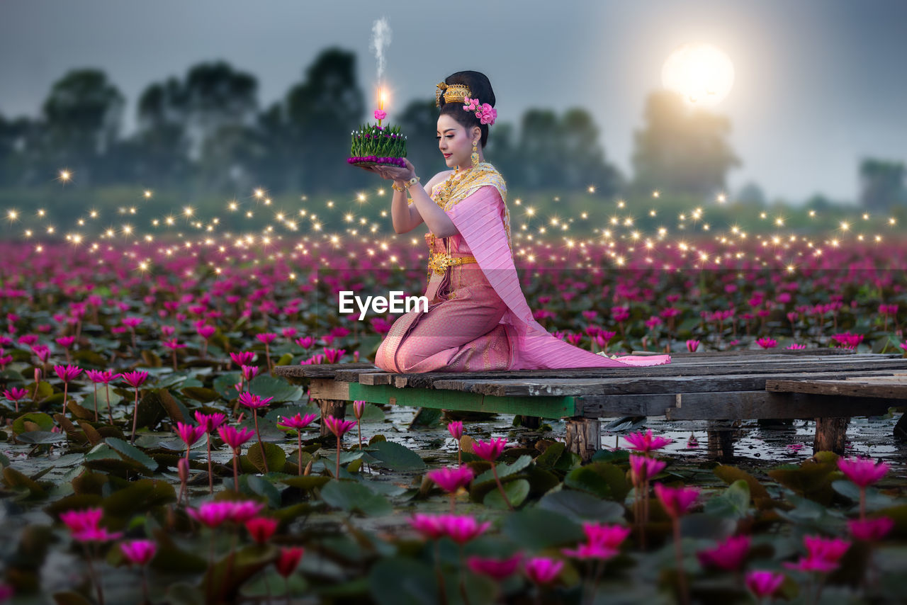 Woman standing by pink flowering plants