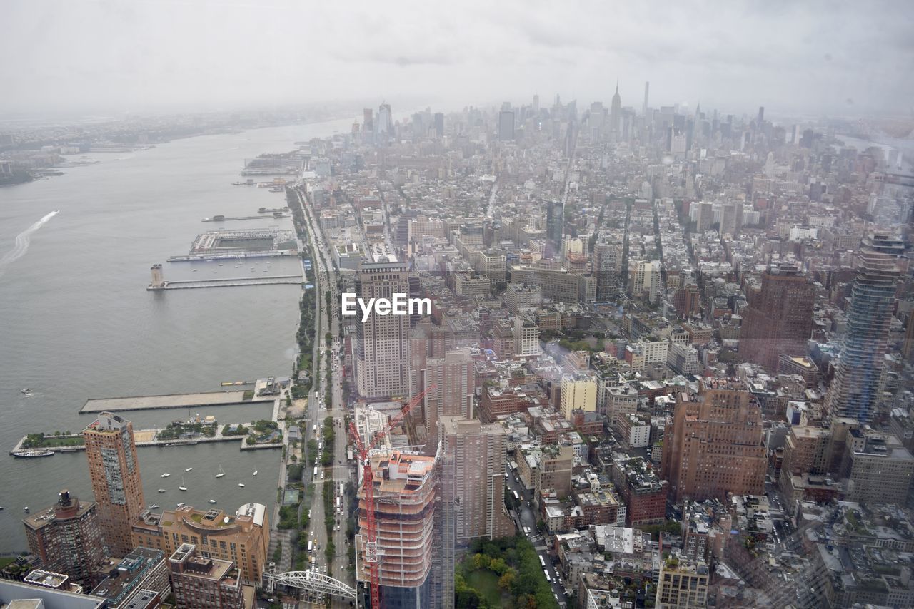 HIGH ANGLE VIEW OF RIVER AMIDST BUILDINGS AGAINST SKY