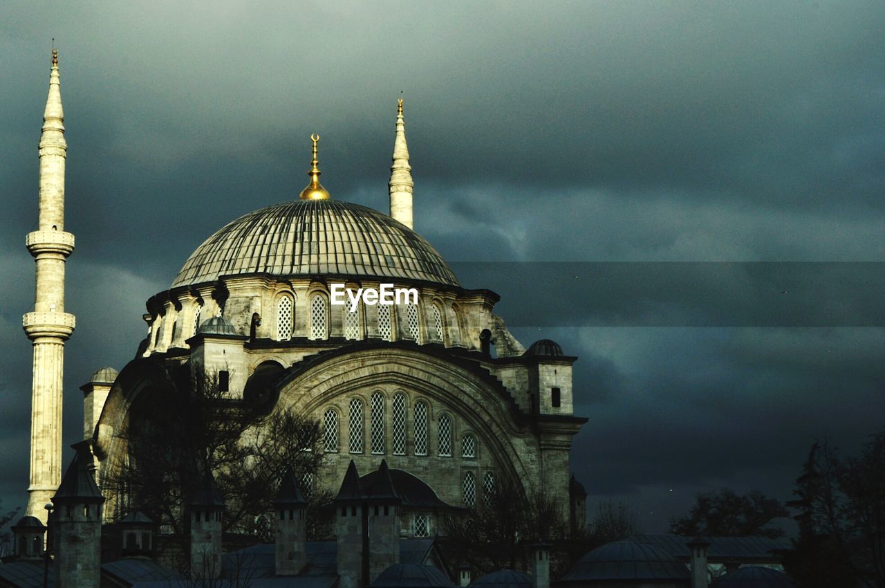 Low angle view of old mosque against cloudy sky