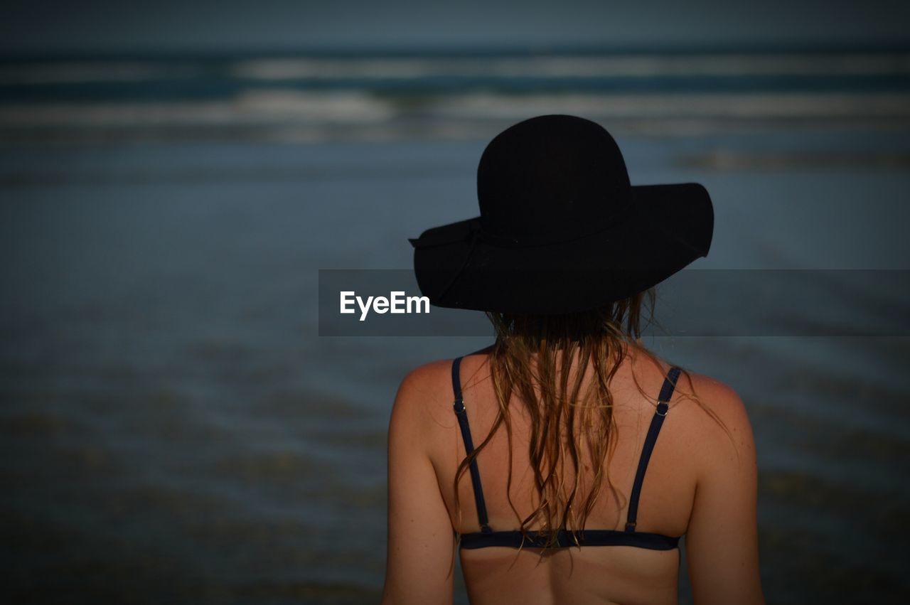 Rear view of woman wearing hat standing on beach