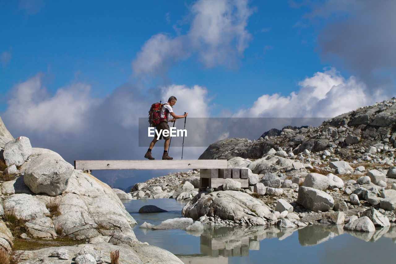 Man standing on rock against sky