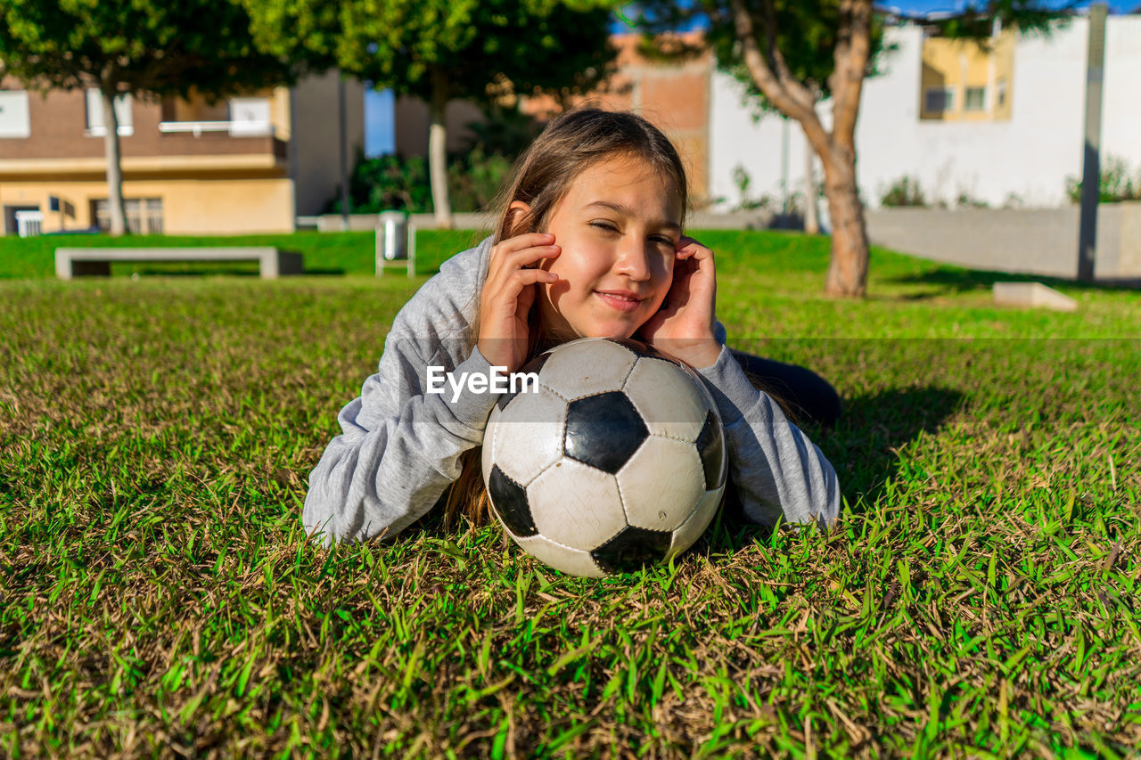 Portrait of smiling girl with ball on grass