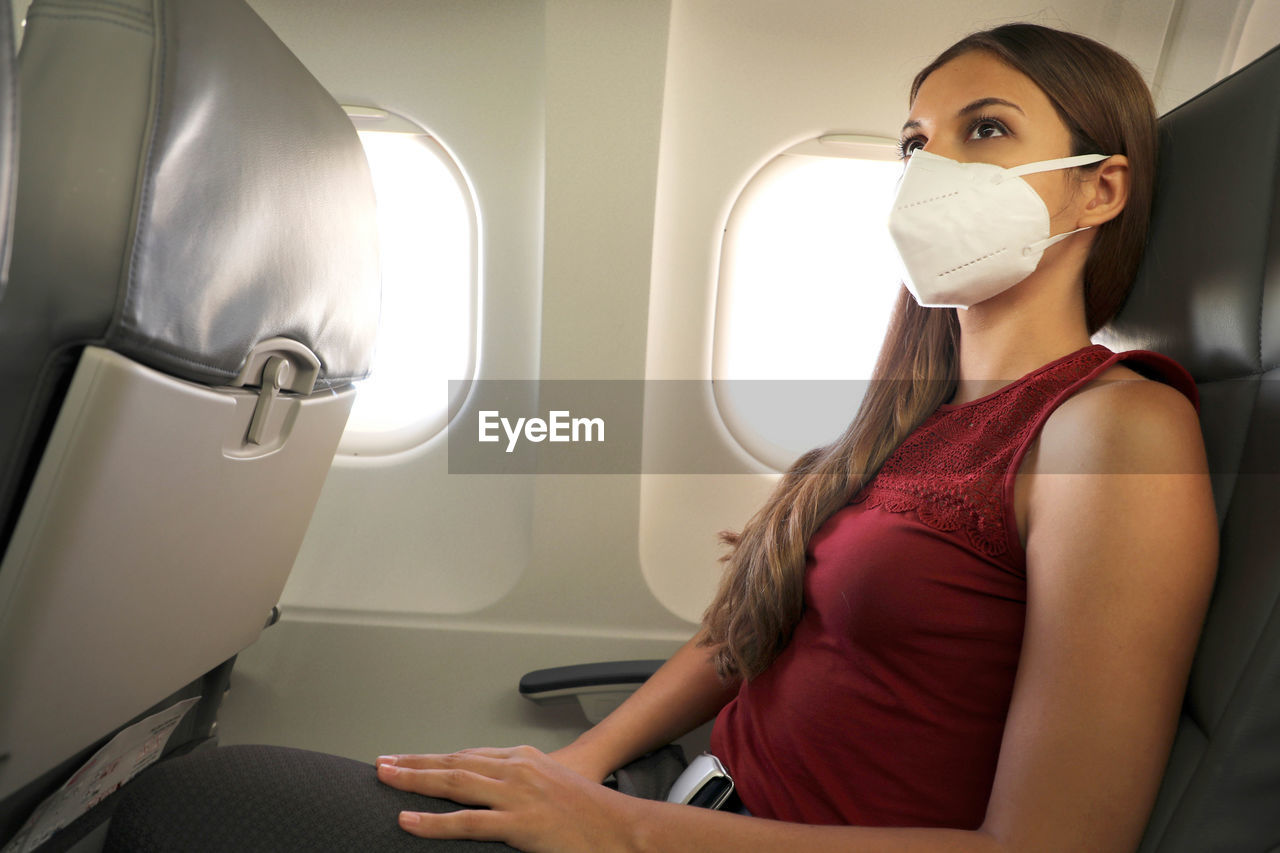 Woman wearing mask sitting in airplane