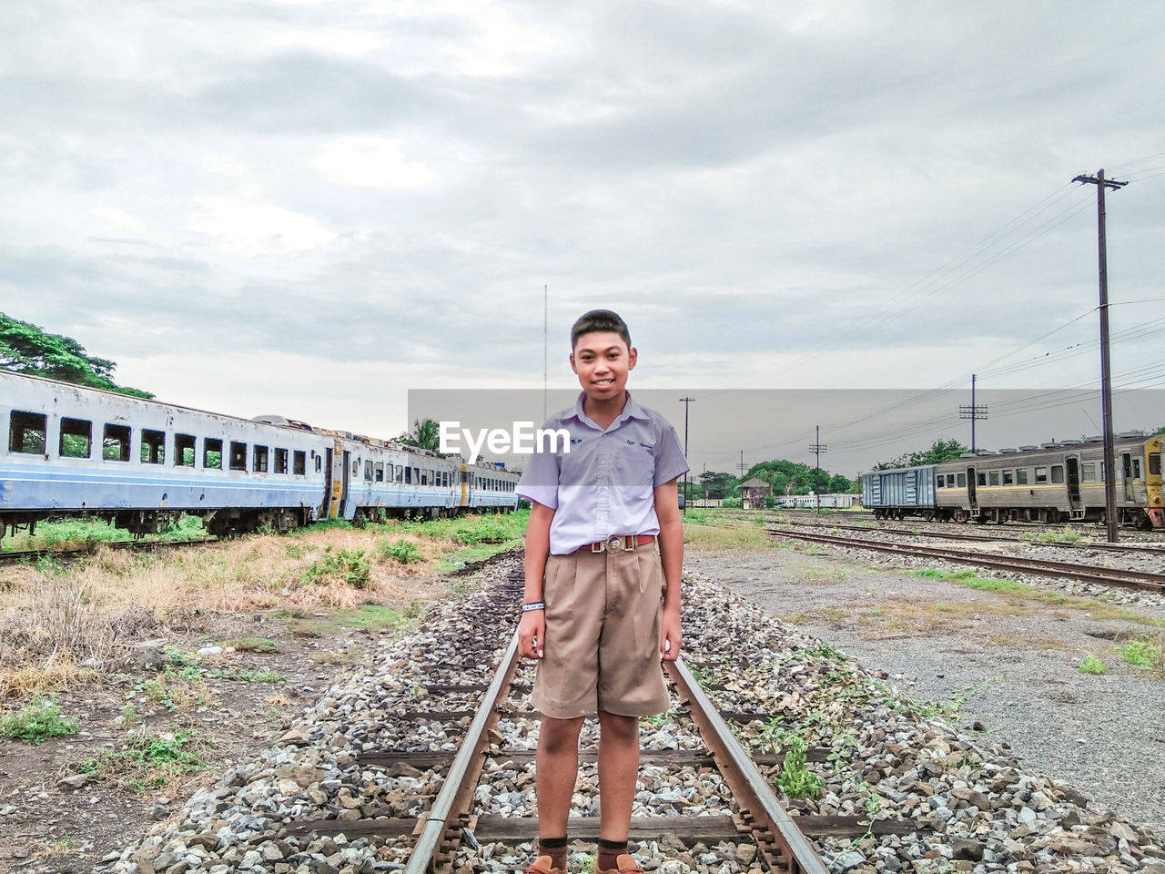 Portrait of man standing on railroad track against sky