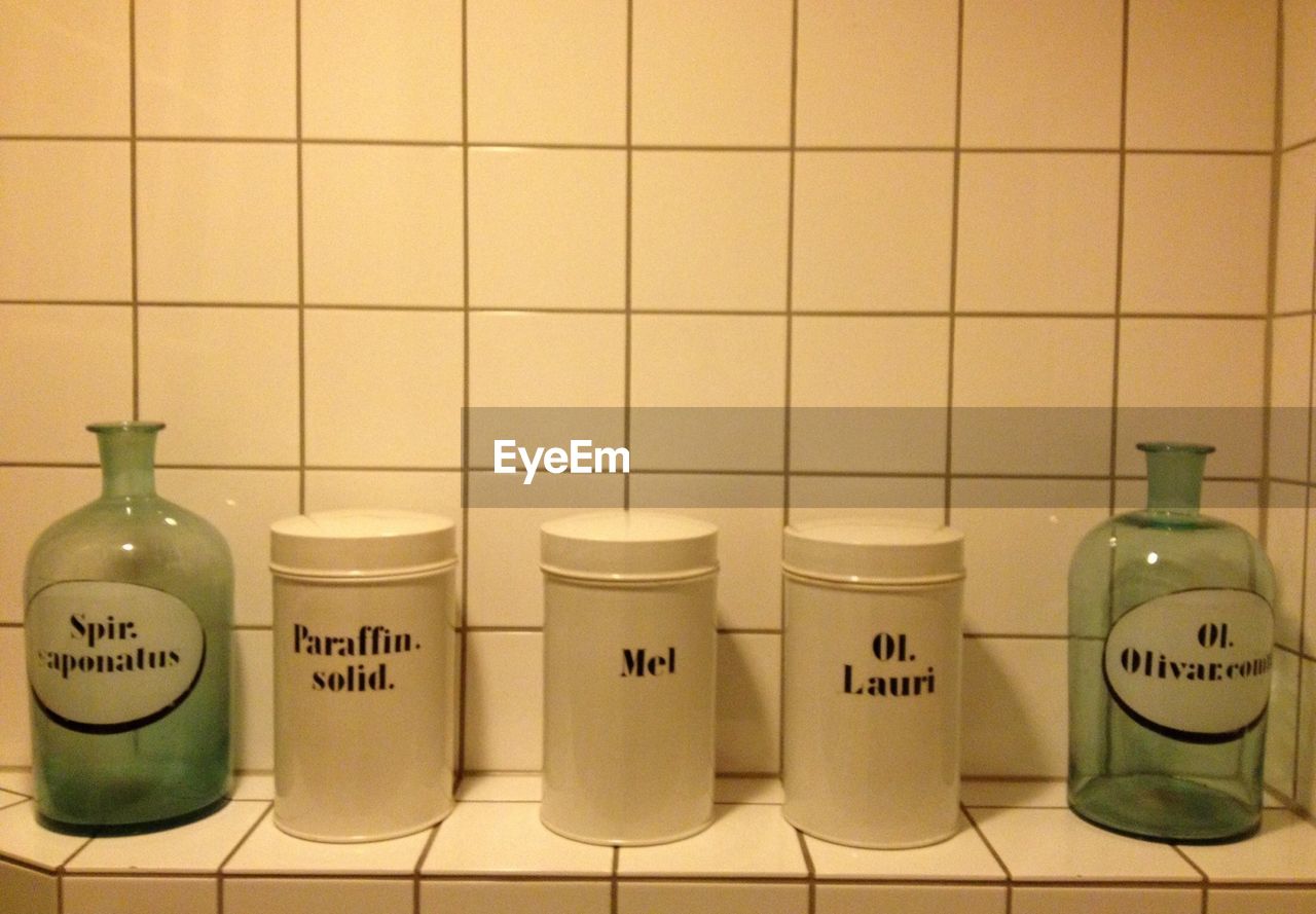 Close-up of containers with jars on tile shelf