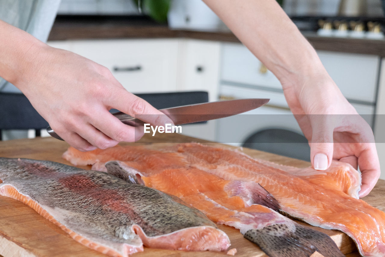 Female hands cutting fillet of red fish. red caviar. removing fish bones. butchering red fish meat.