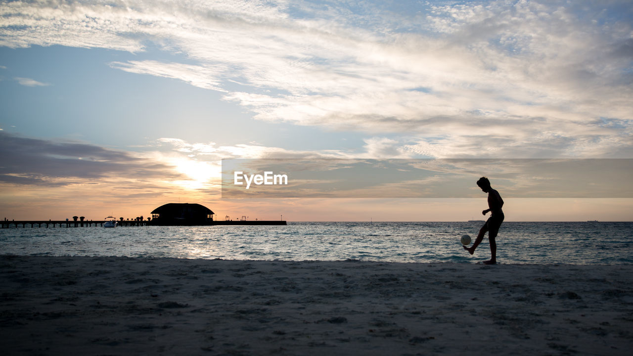 Silhouette of man on beach against sky during sunset