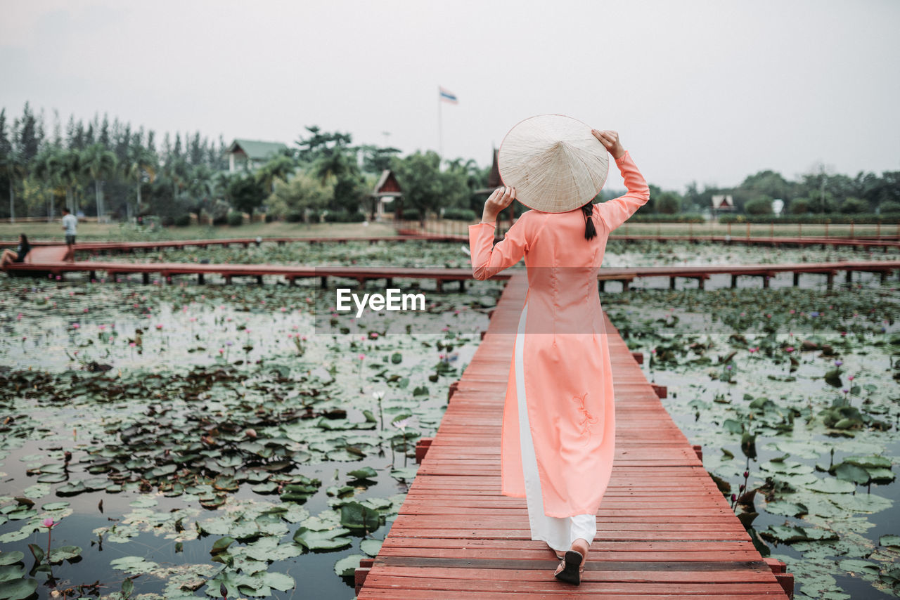 FULL LENGTH OF WOMAN STANDING AGAINST PLANTS