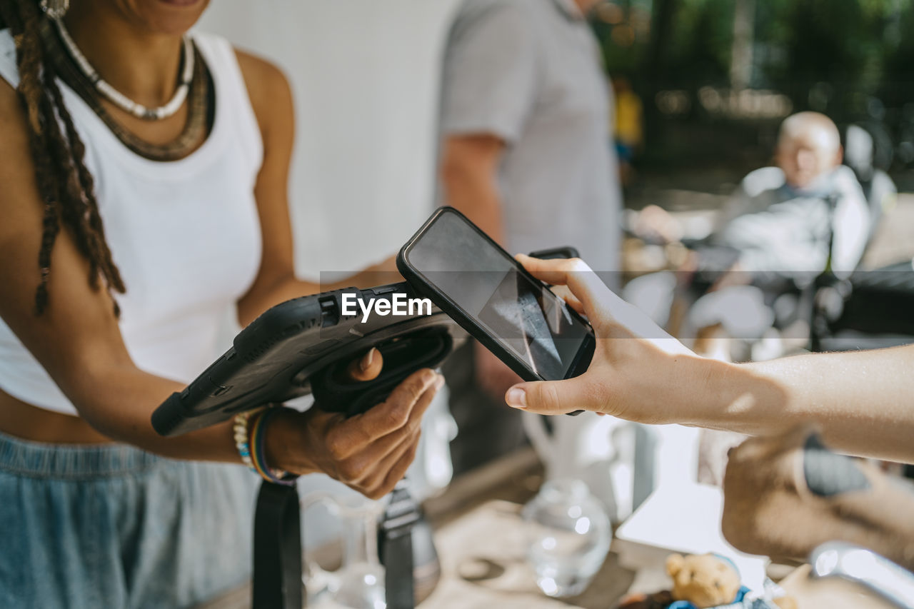 Hand of woman doing contactless payment while shopping at flea market