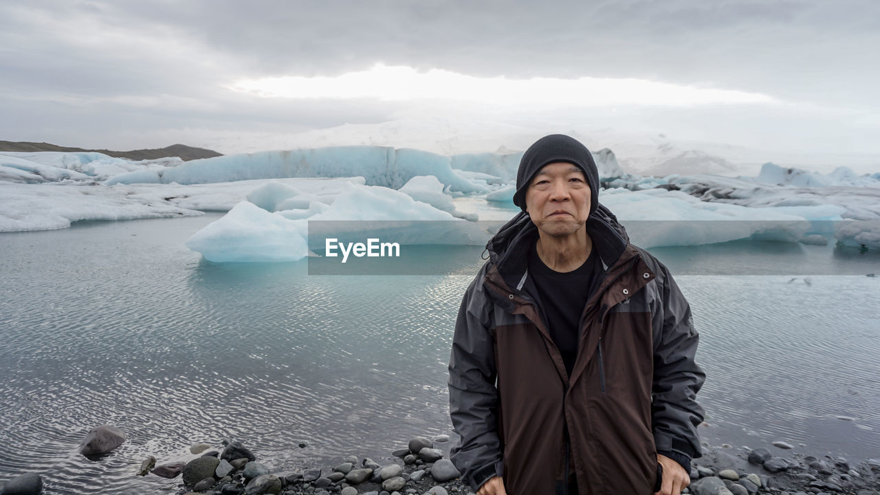 Mature man standing against glacier